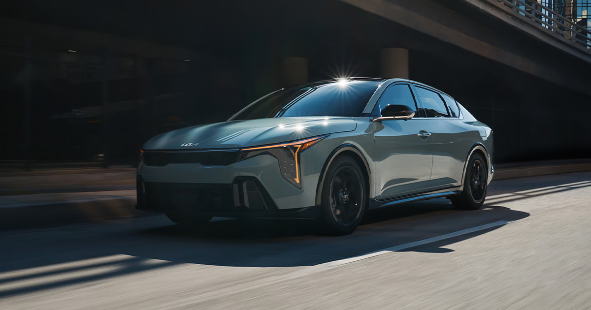 A 2025 Kia K4 driving down the highway through city streets.