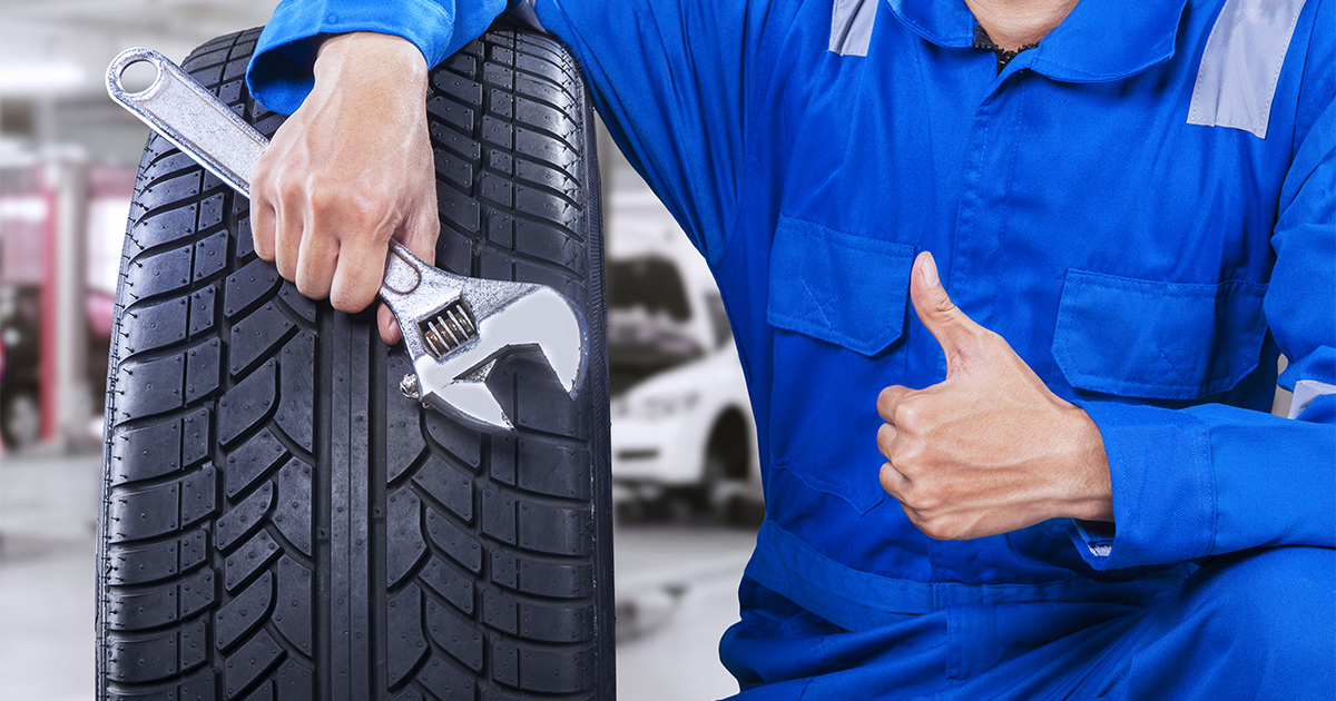 A service technician posing with his tools next to a tire